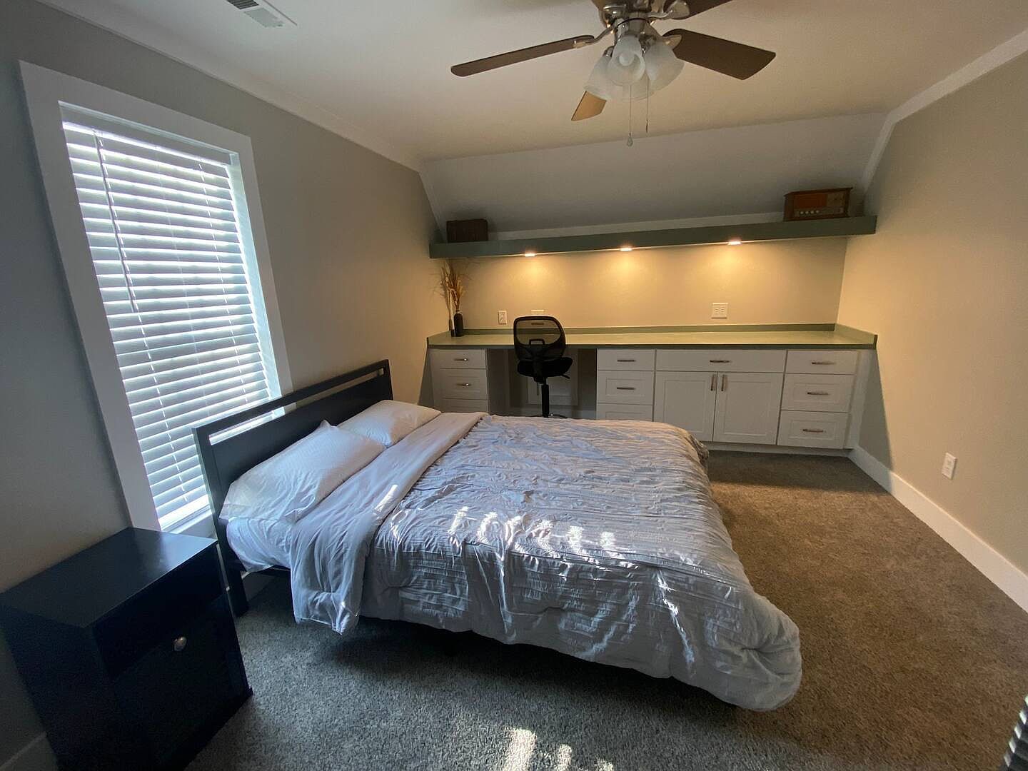 A bedroom with built-in desk and shelving