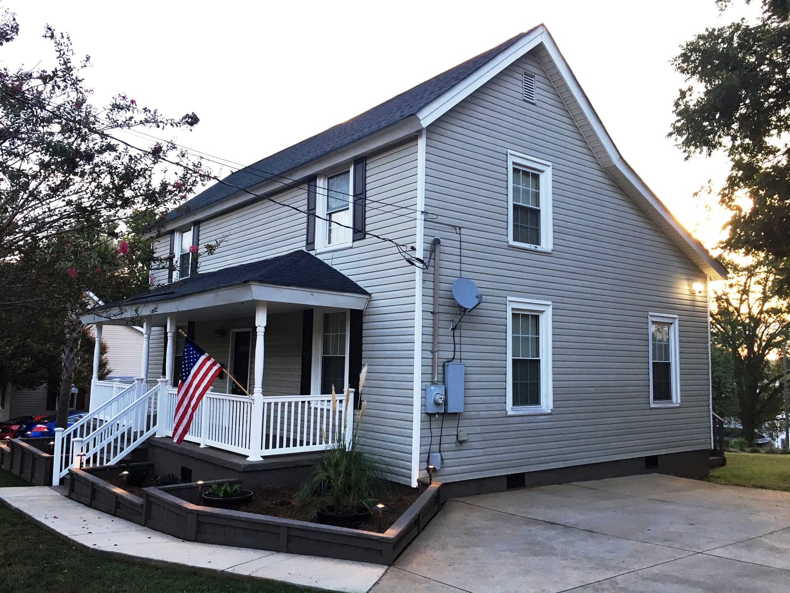 The front of the house — covered porch, white railings, and landscaped beds