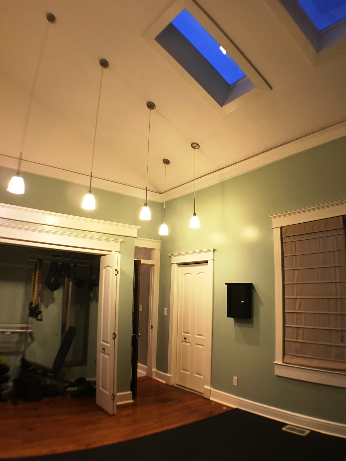 A vaulted bonus room with pendant lighting and skylights